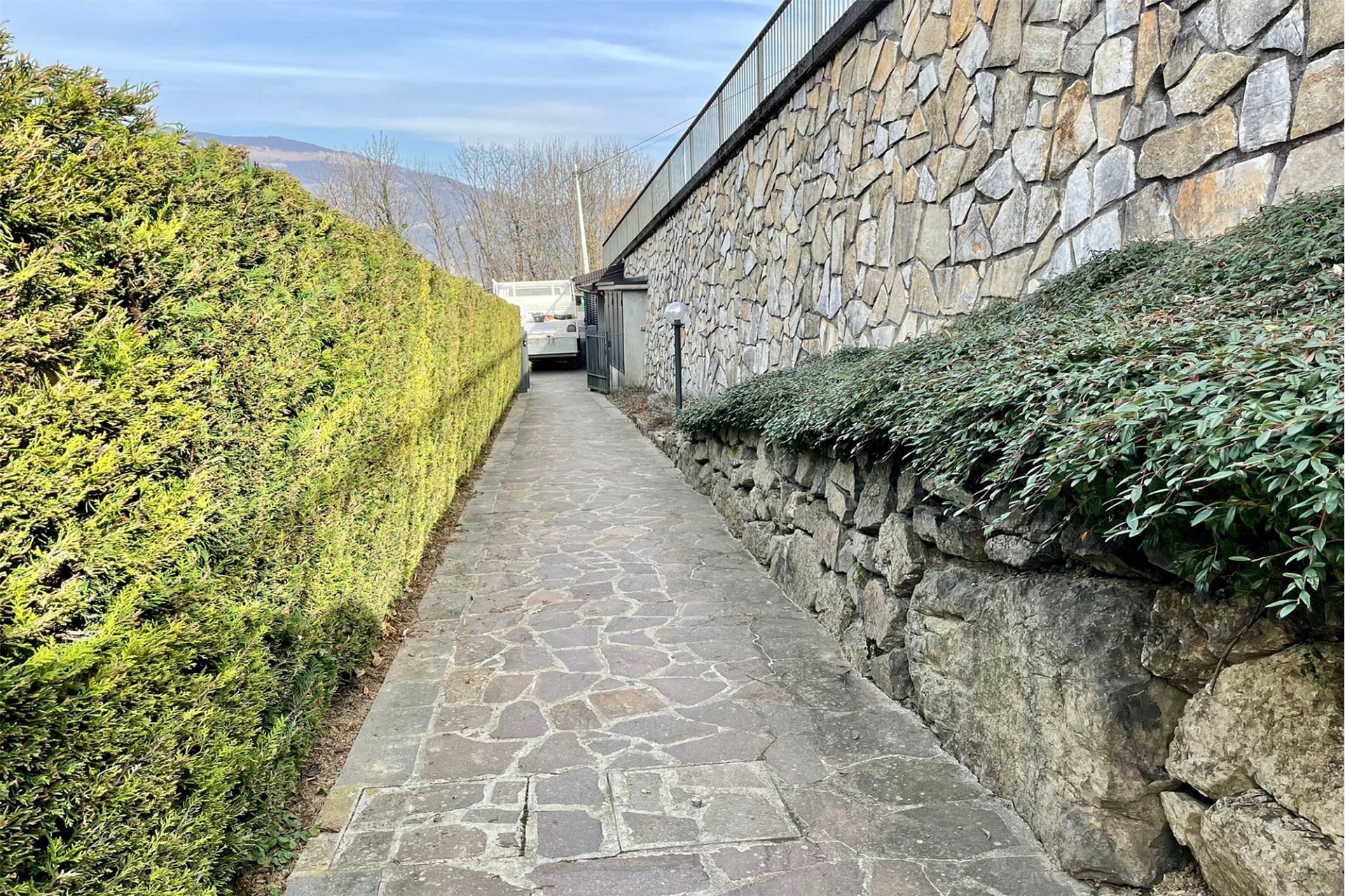 Außenweg mit Natursteinmauer und Hecken