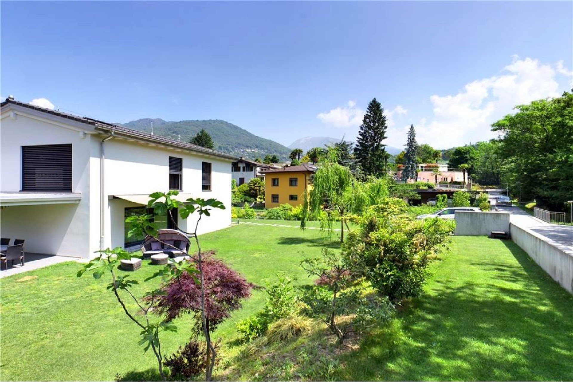 Gepflegter Garten mit moderner Wohnbebauung und Bergblick
