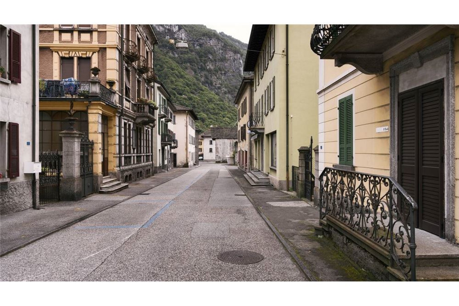 Straßenansicht in einem eng bebauten Ort mit Bergkulisse