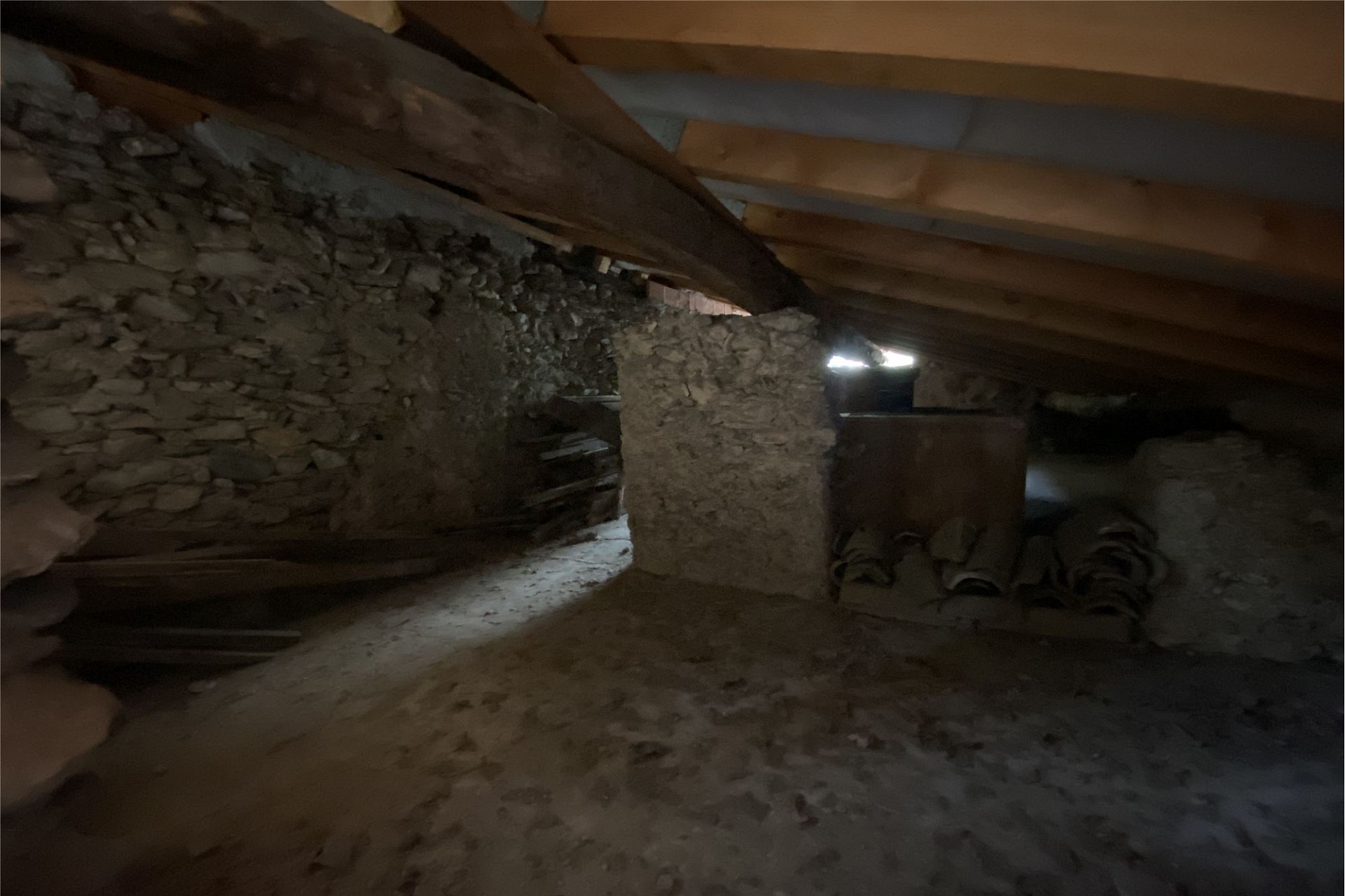Dunkler Dachboden mit Steinmauer und Holzbalken