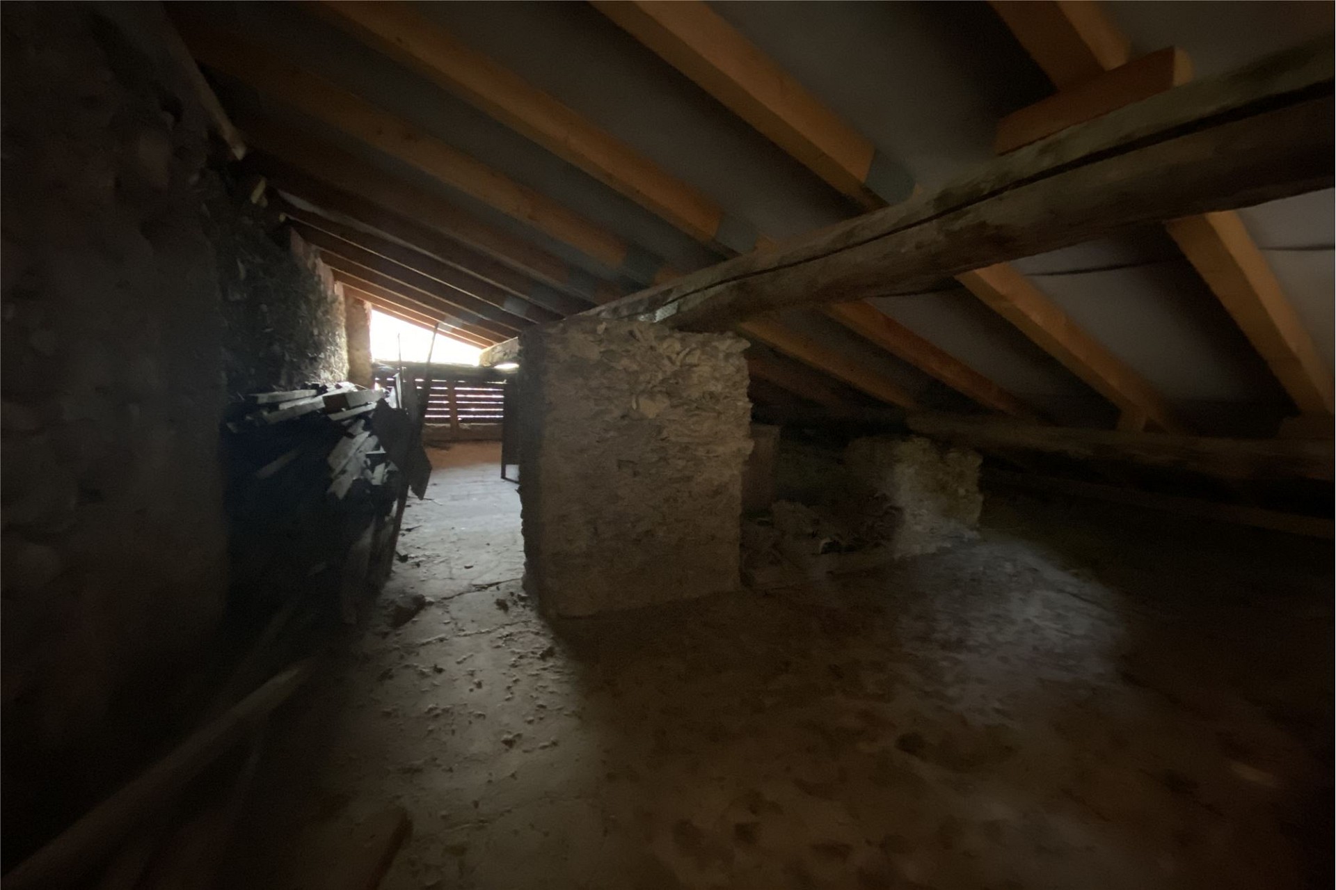 Dachboden mit sichtbaren Holzbalken und Steinsäulen