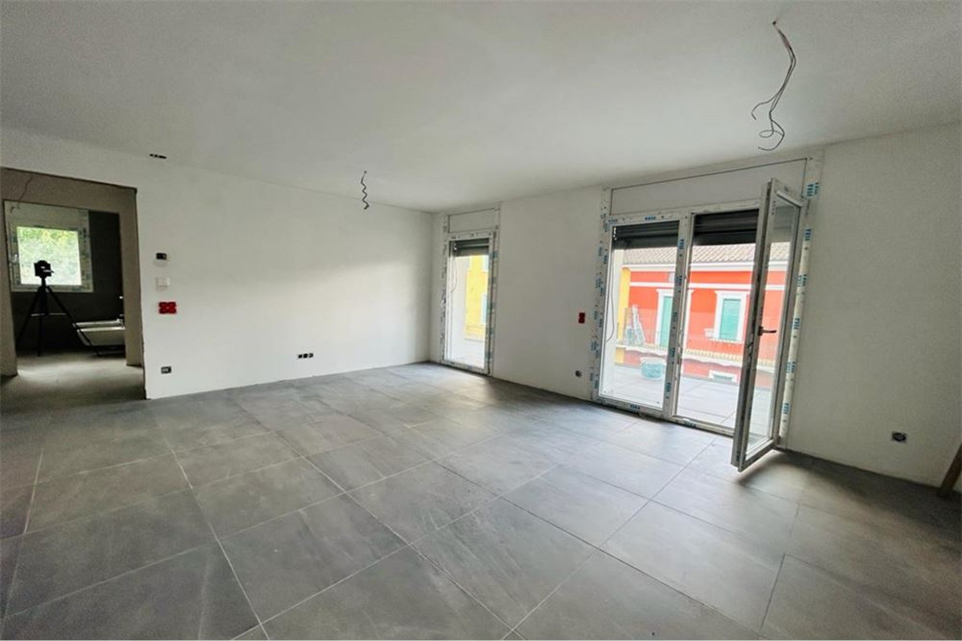 Leerer Wohnraum im Neubau mit Balkonzugang
