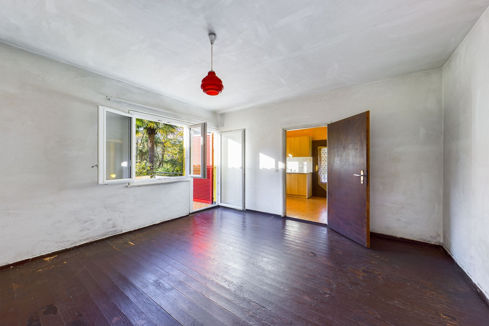 Leeres Zimmer mit dunklem Holzboden und offenem Fenster
