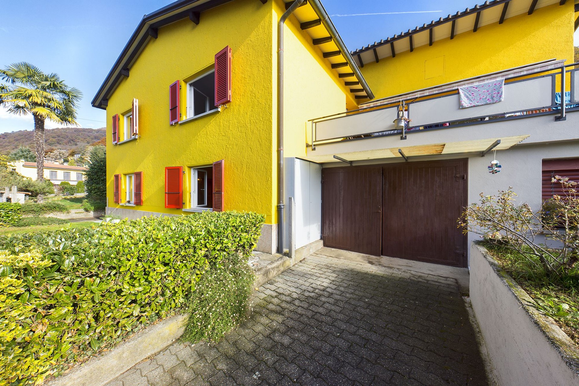 Gelbes Wohnhaus mit Balkon und Garage