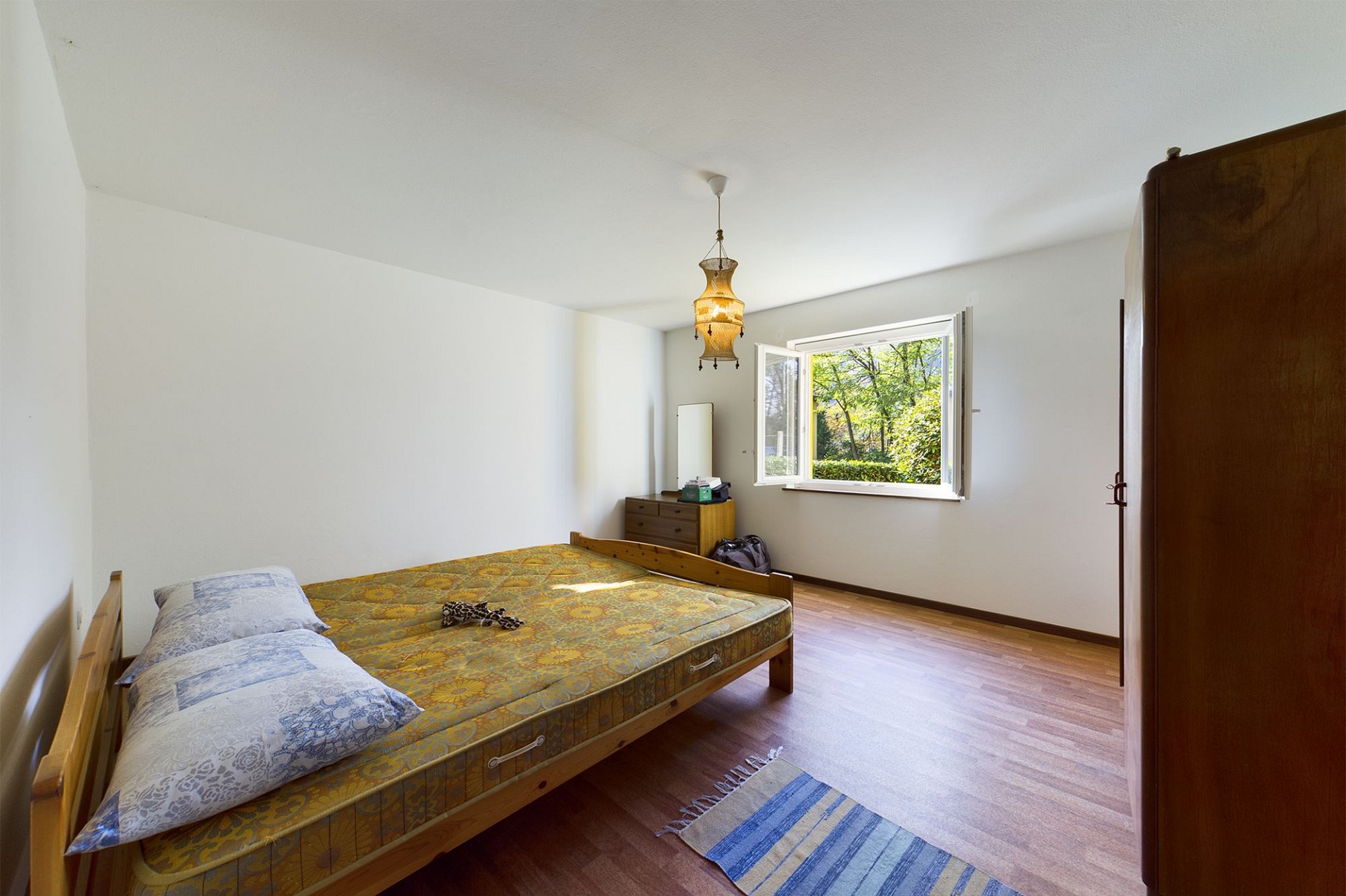 Schlichtes Schlafzimmer mit Holzbett und Naturblick
