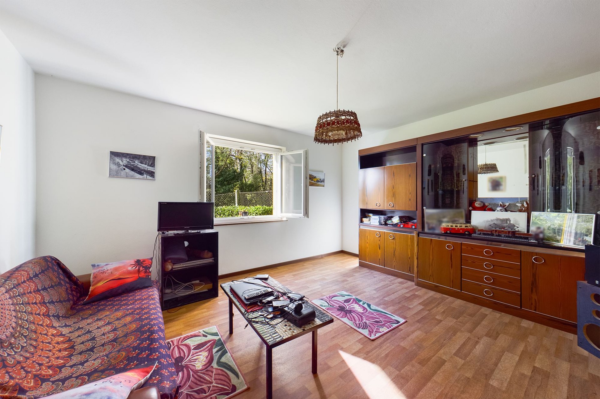 Wohnzimmer mit offener Fensterfront und Holzschrankwand