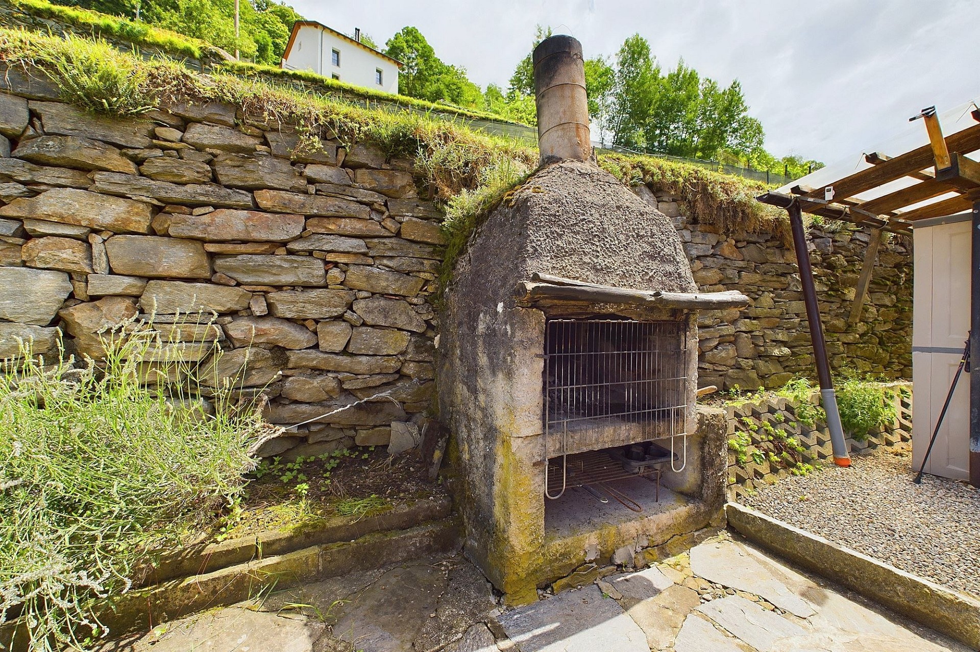 Außenbereich mit rustikalem Ofen und Natursteinmauer