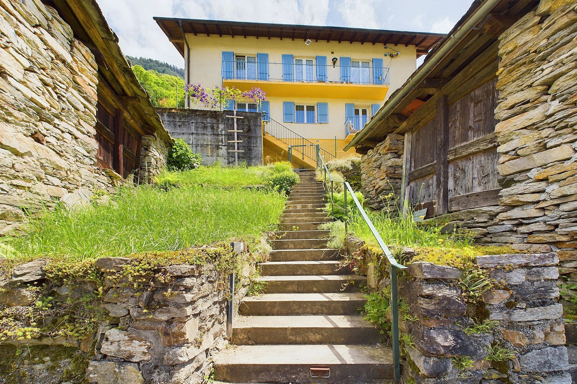 Außenansicht eines Hauses mit Steintreppe und Hanggrundstück