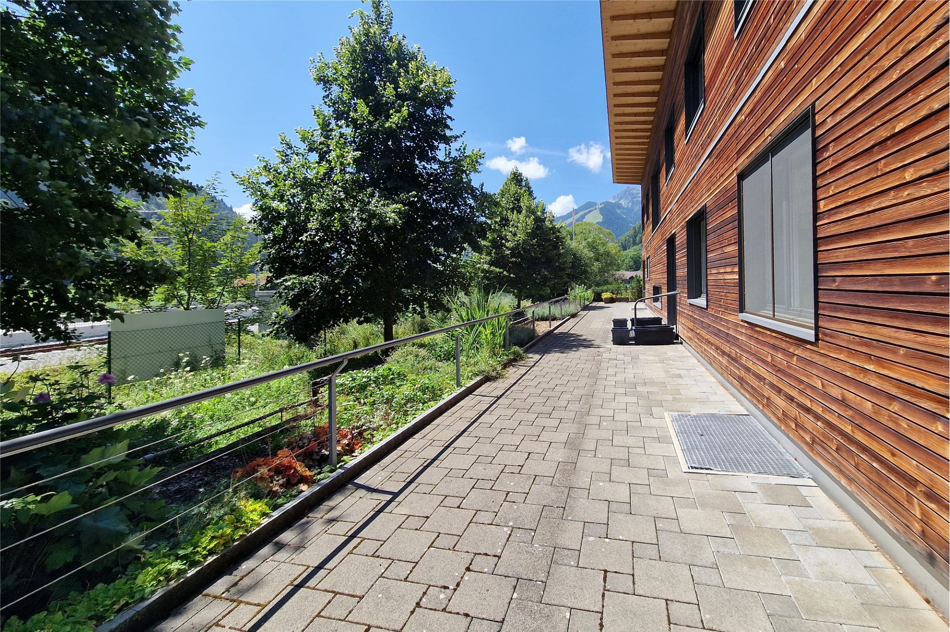 Außenansicht einer Holzfassade mit Gartenweg