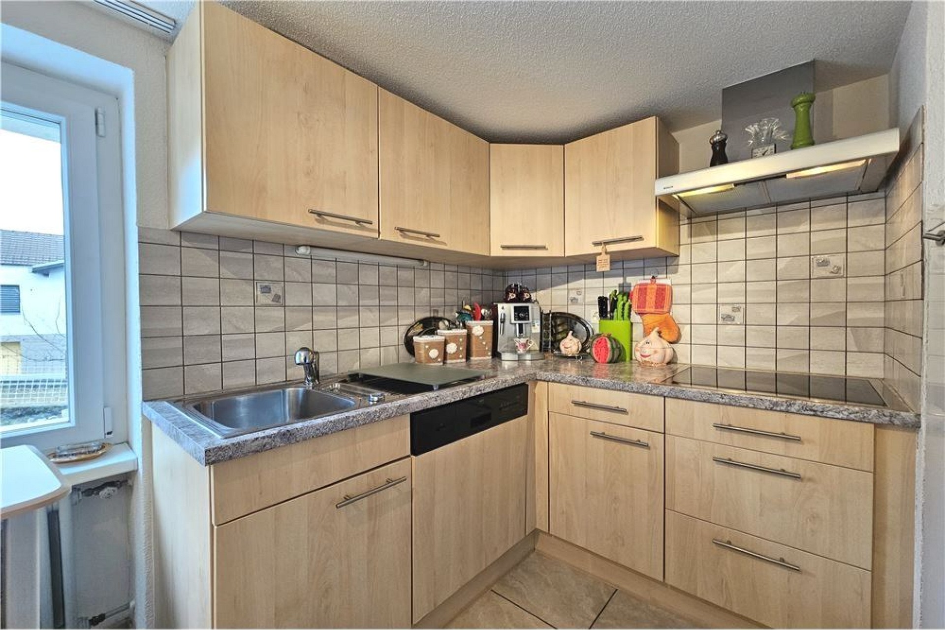Kleine L-förmige Küche mit hellem Holz und Fliesenrückwand