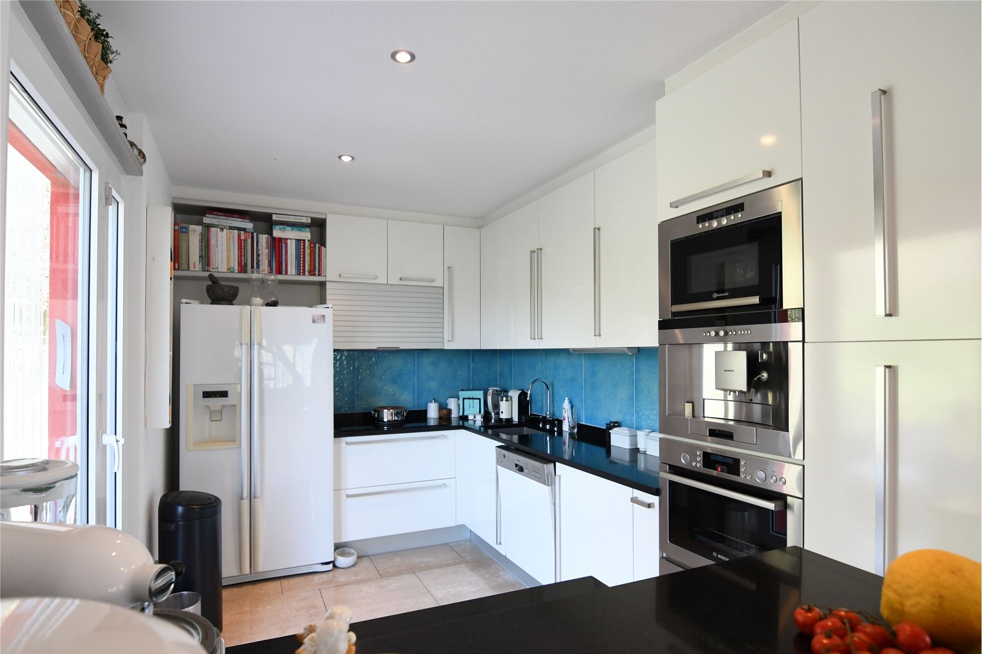 Moderne Küche mit weißen Fronten und blauer Rückwand
