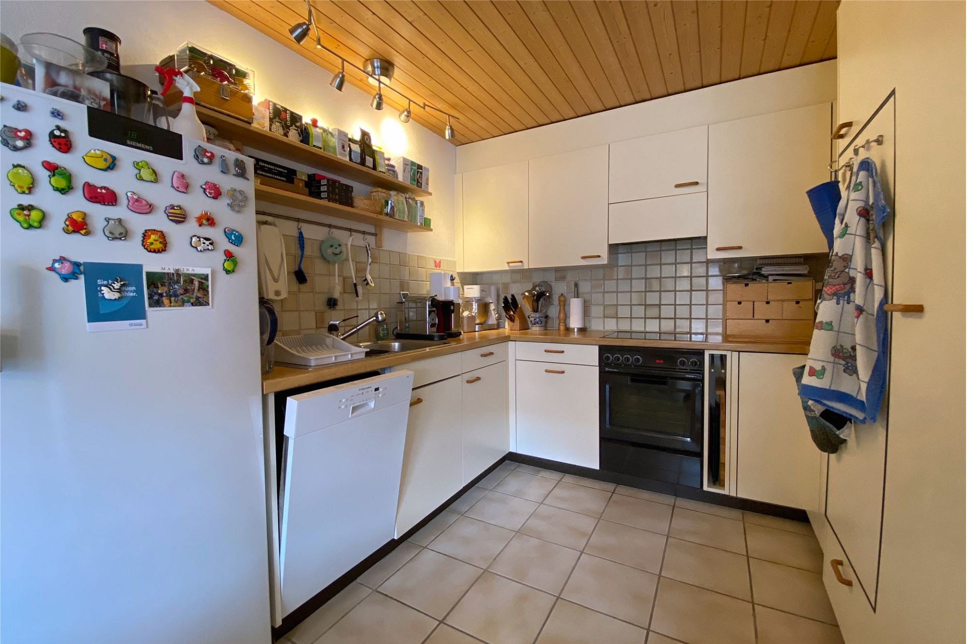 Kleine Eckküche mit weißen Fronten und Holzdecke