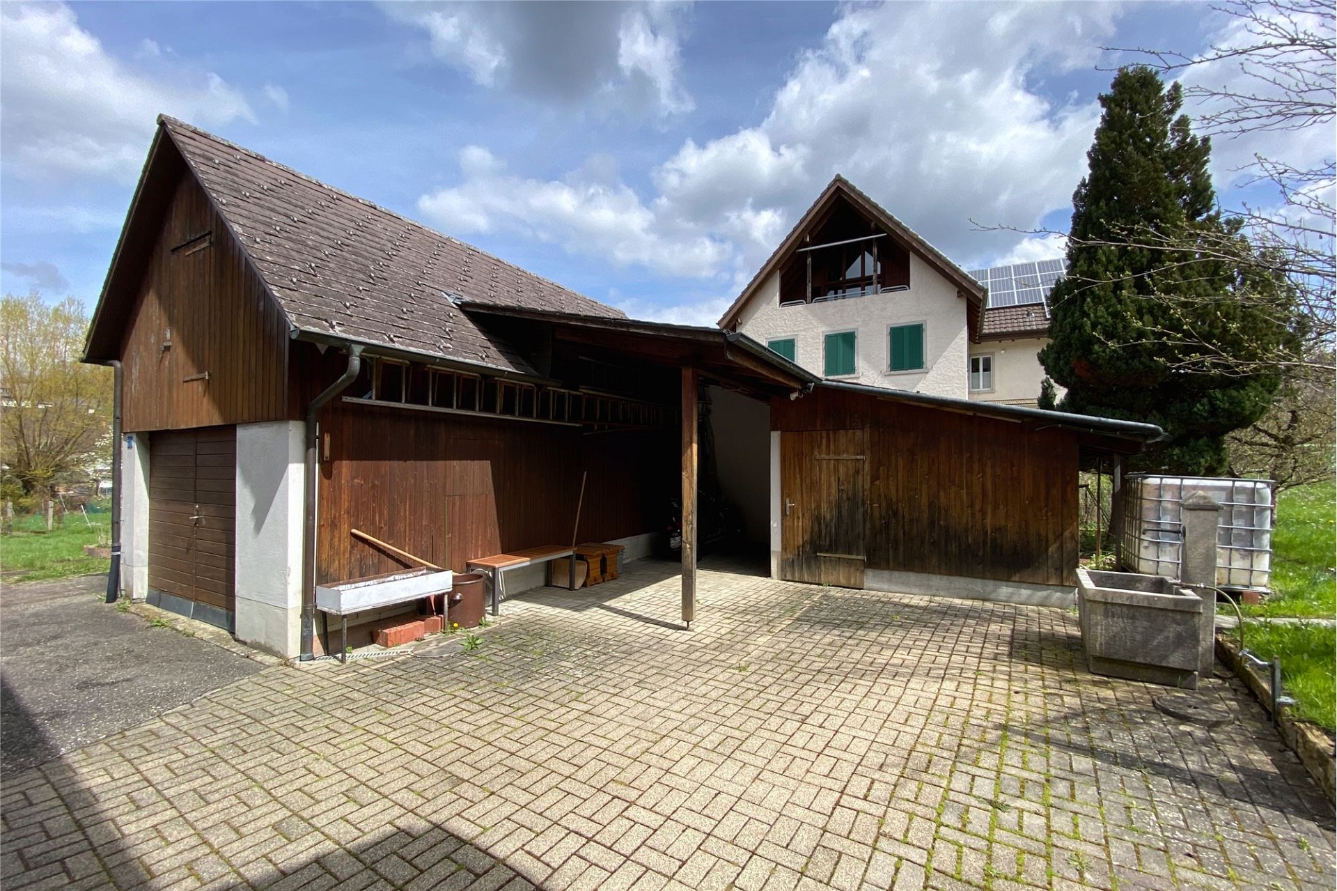 Außenansicht eines ländlichen Anwesens mit Nebengebäude und Hof