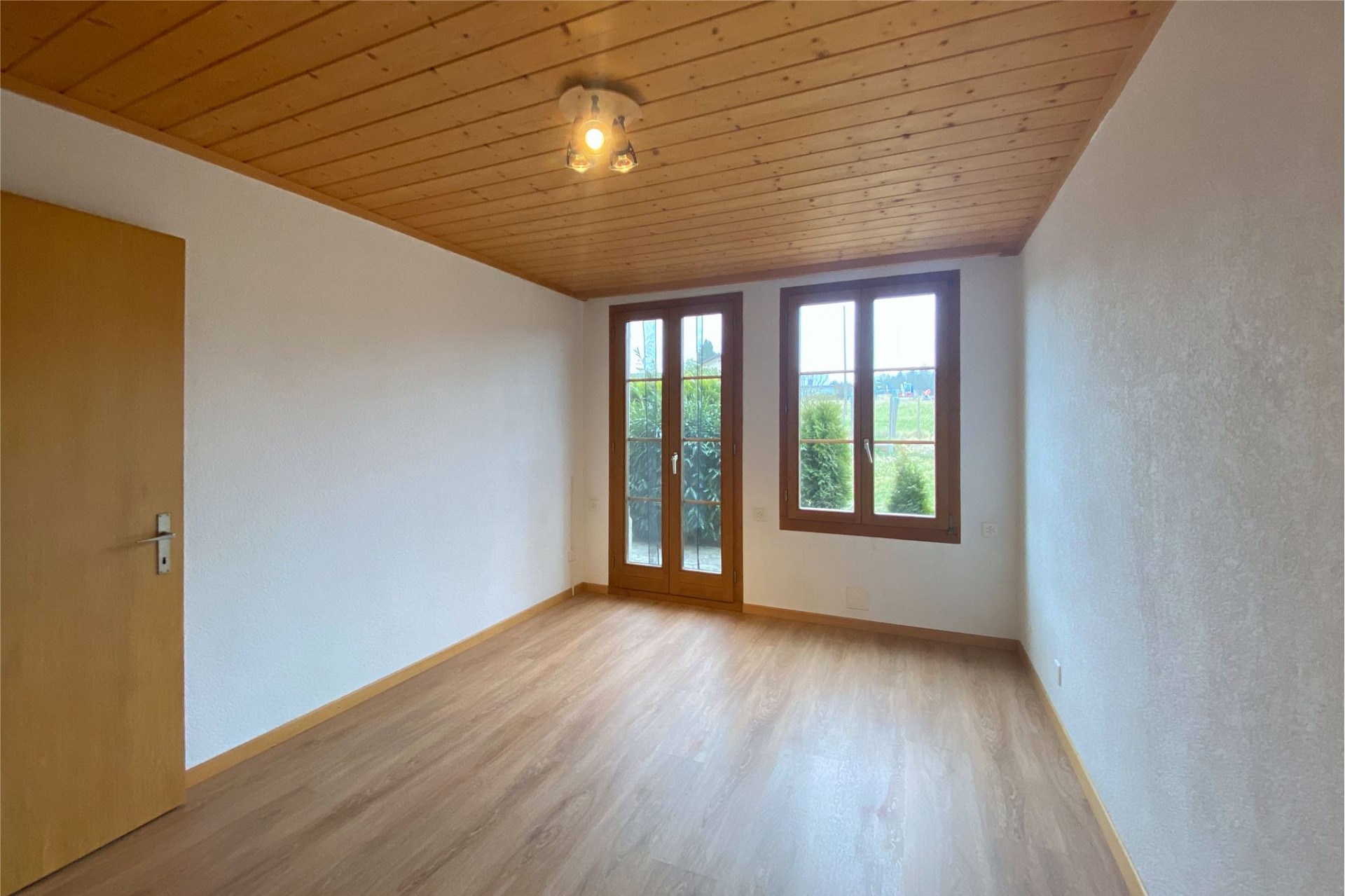 Leerer Wohnraum mit Holzdecke und Blick ins Grüne