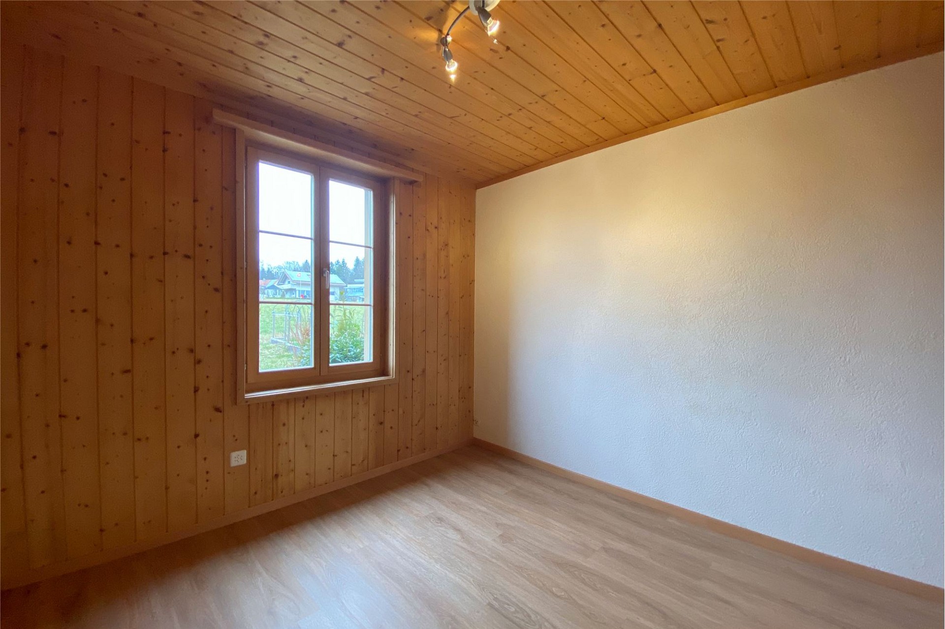 Leerer, holzverkleideter Raum mit Fenster
