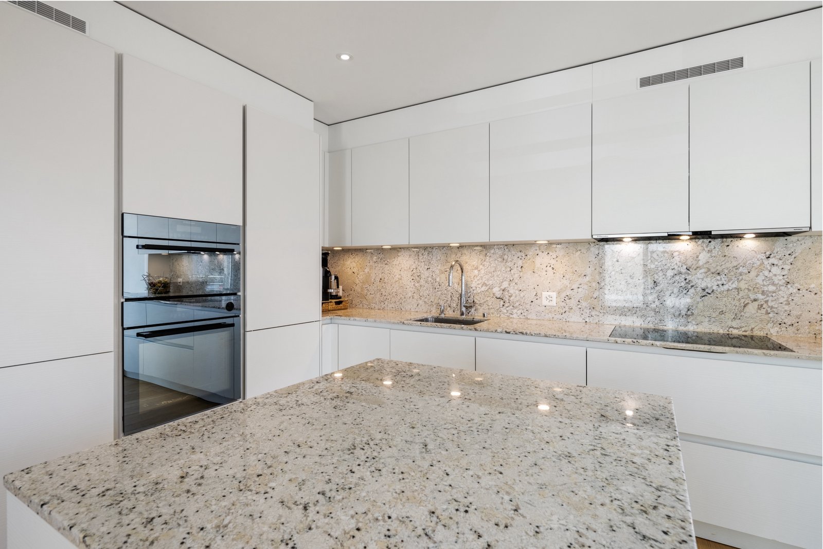 Moderne weiße Designküche mit Granitinsel