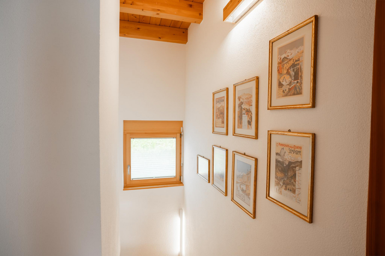 Heller Treppenflur mit Holzbalken und gerahmten Bildern
