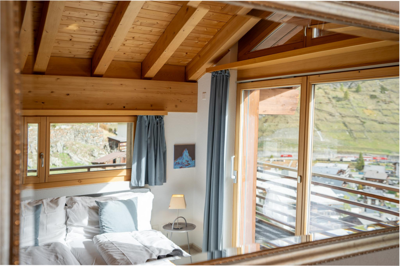 Gemütliches Schlafzimmer mit Holzbalkendecke und Bergblick