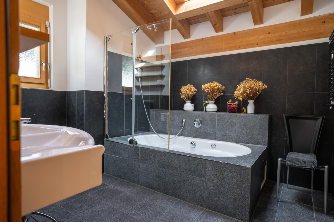 Modernes Badezimmer mit Badewanne und Holzbalkendecke