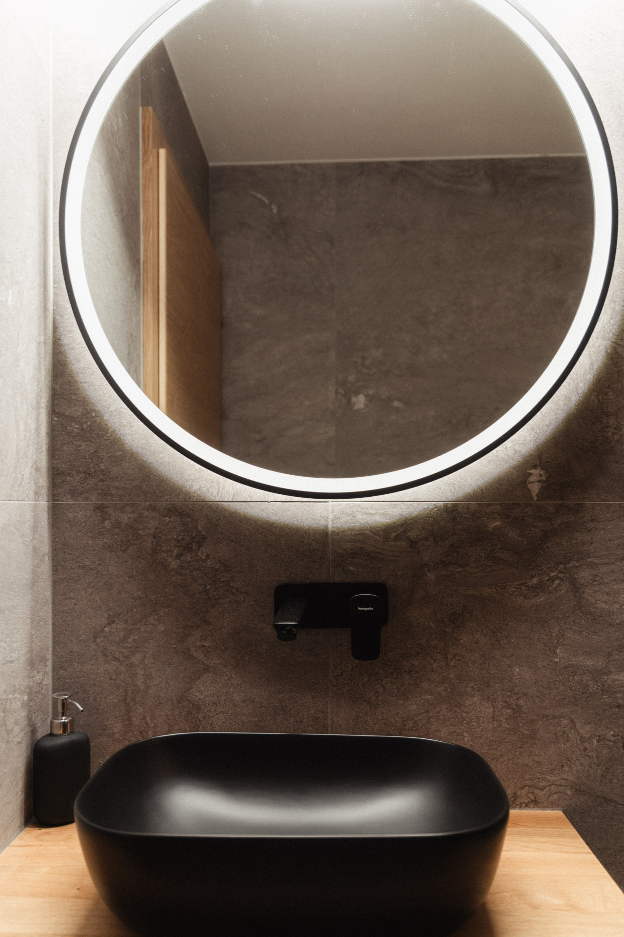 Modernes Badezimmer mit runder Leuchtspiegel und schwarzem Aufsatzbecken