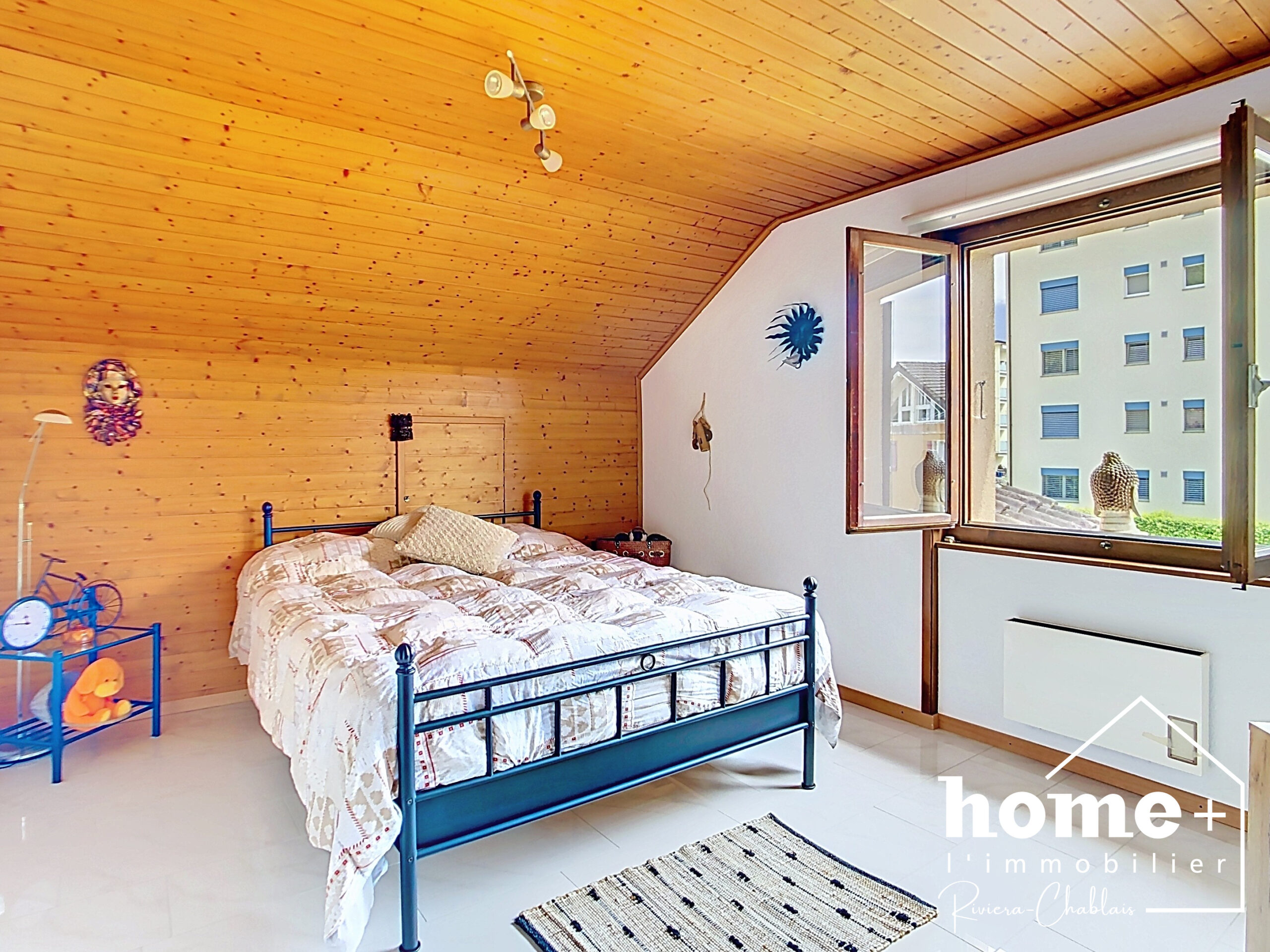 Dachzimmer mit Bett und offenem Fenster