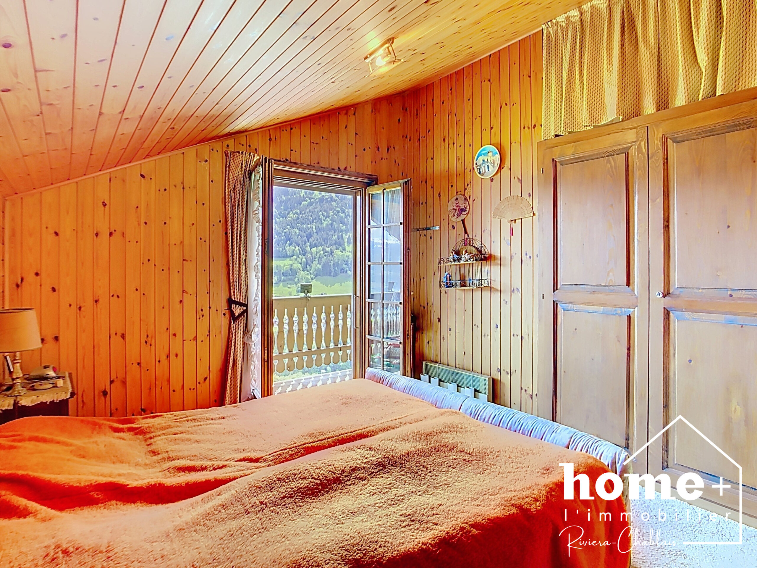 Gemütliches Schlafzimmer mit Holzvertäfelung und Balkonblick