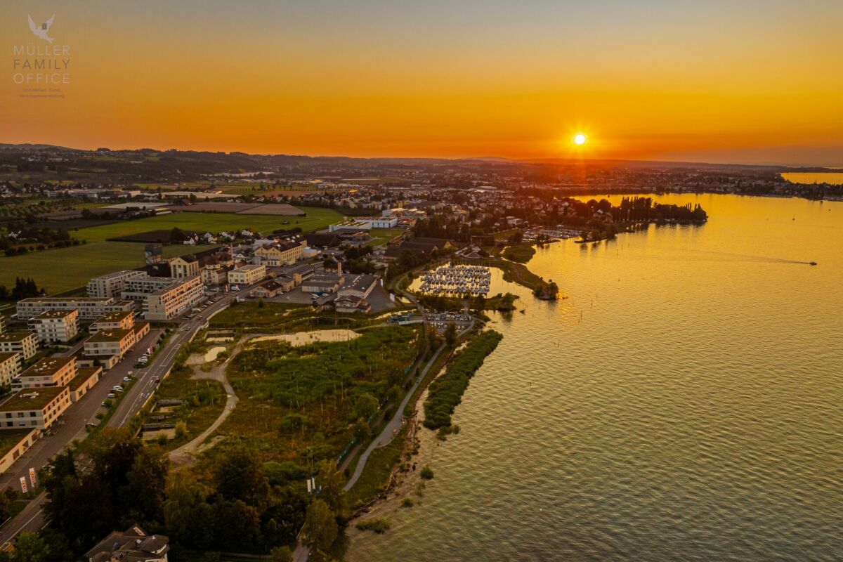 Luftaufnahme bei Sonnenuntergang über Seeufer und Siedlung
