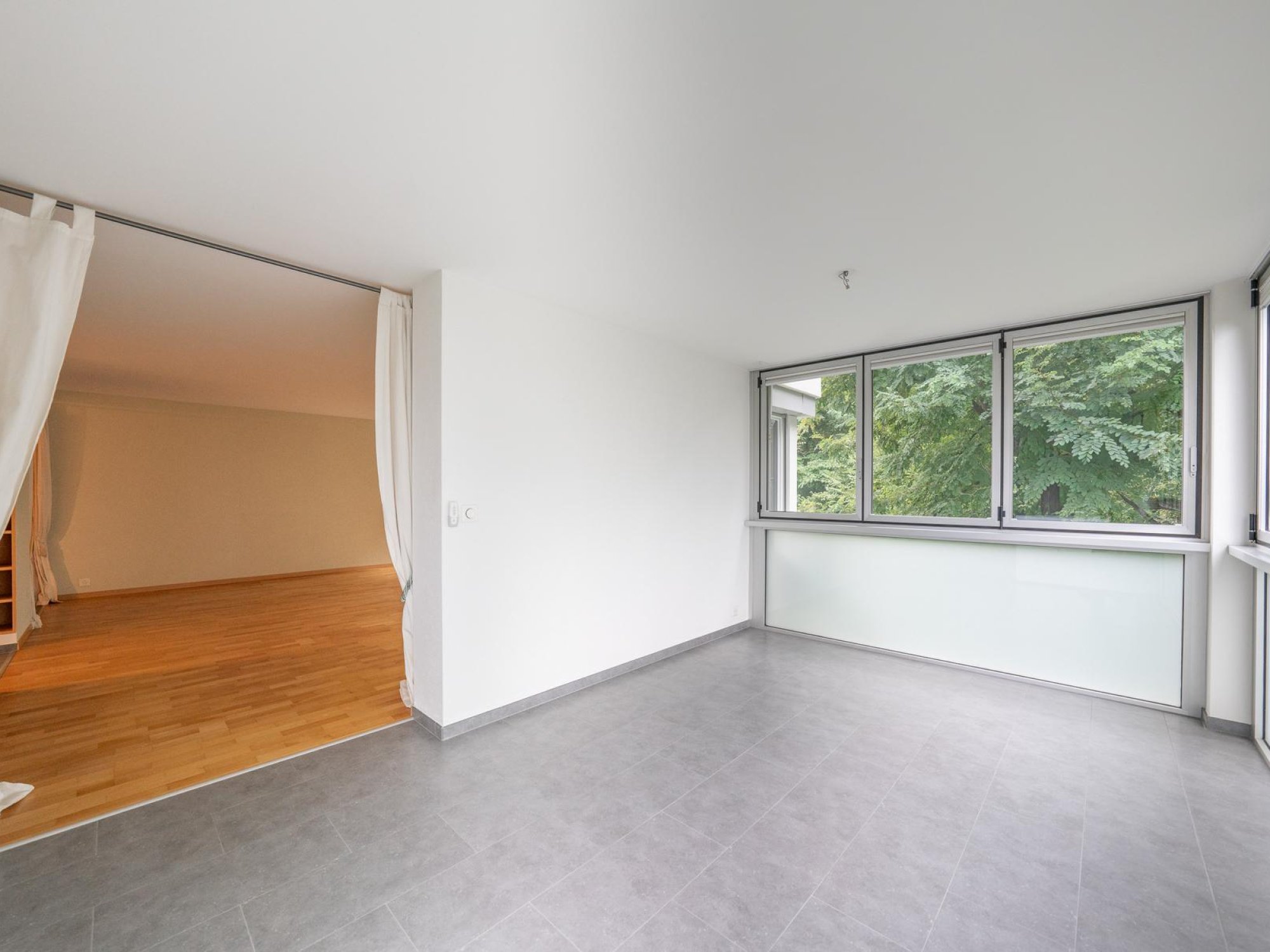 Heller, leerer Wohnraum mit großem Fensterbereich