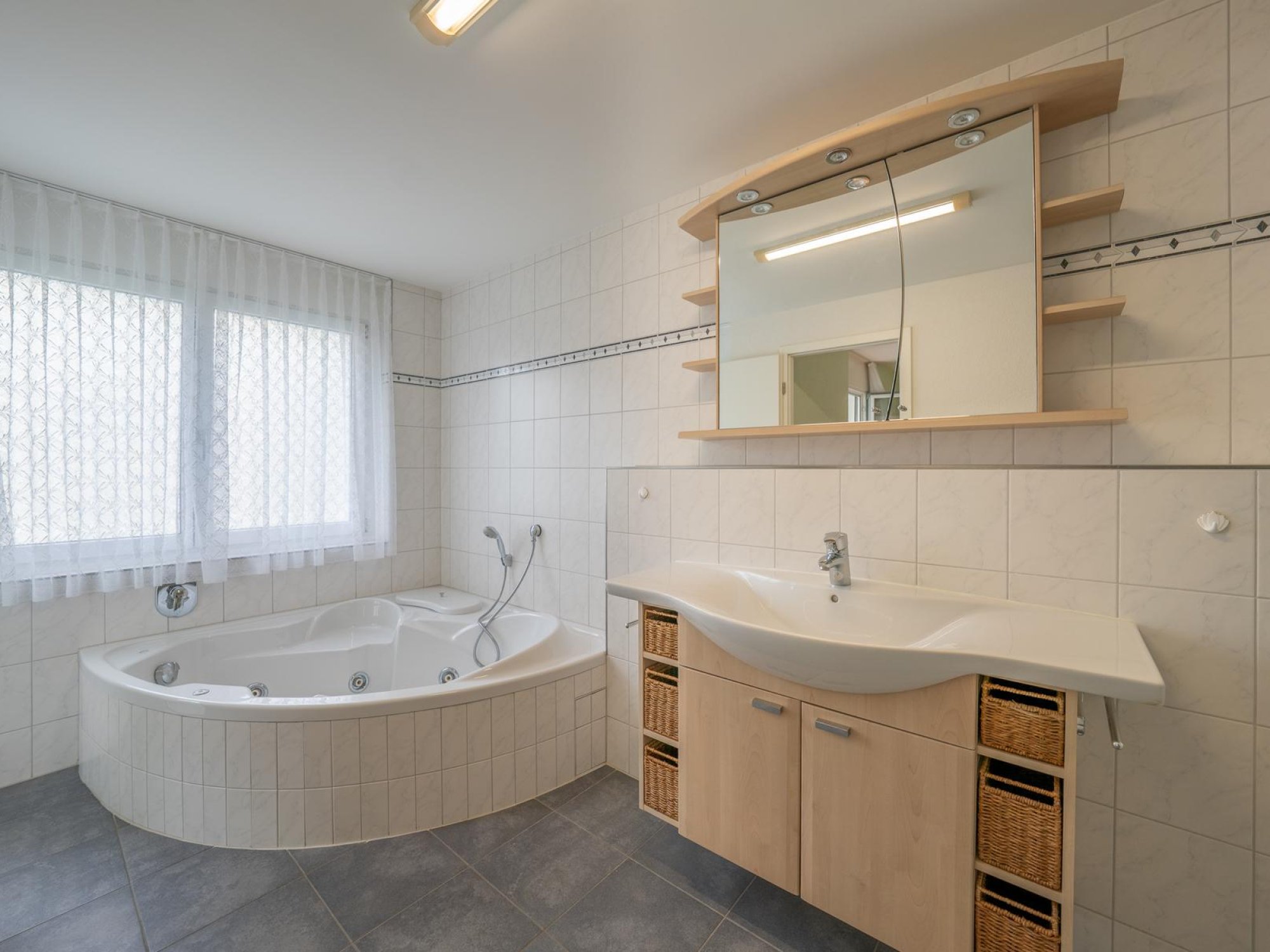 Helles Badezimmer mit Eckbadewanne und Waschtisch