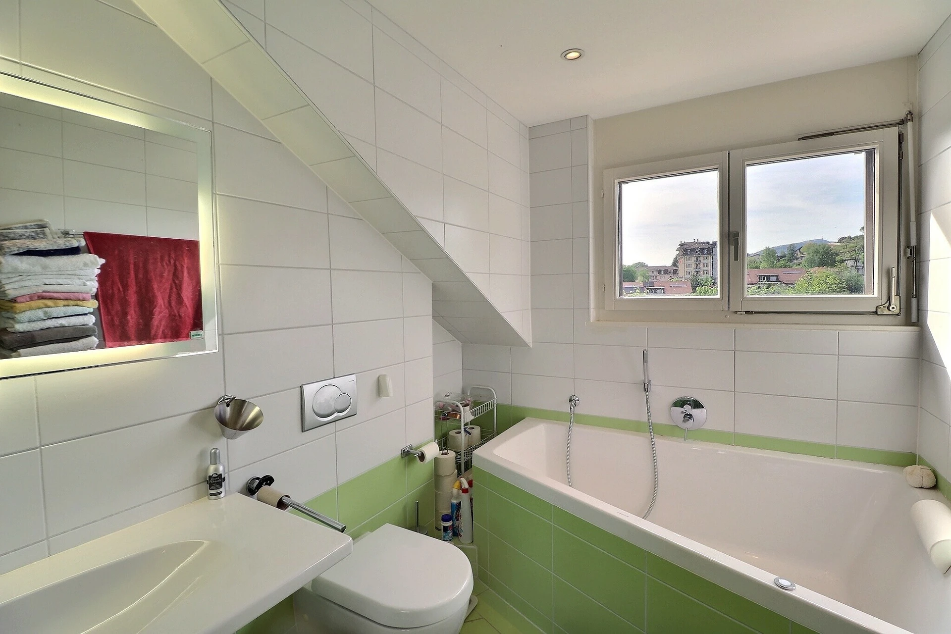 Helles Badezimmer mit grün-weißen Fliesen und Dachfenster