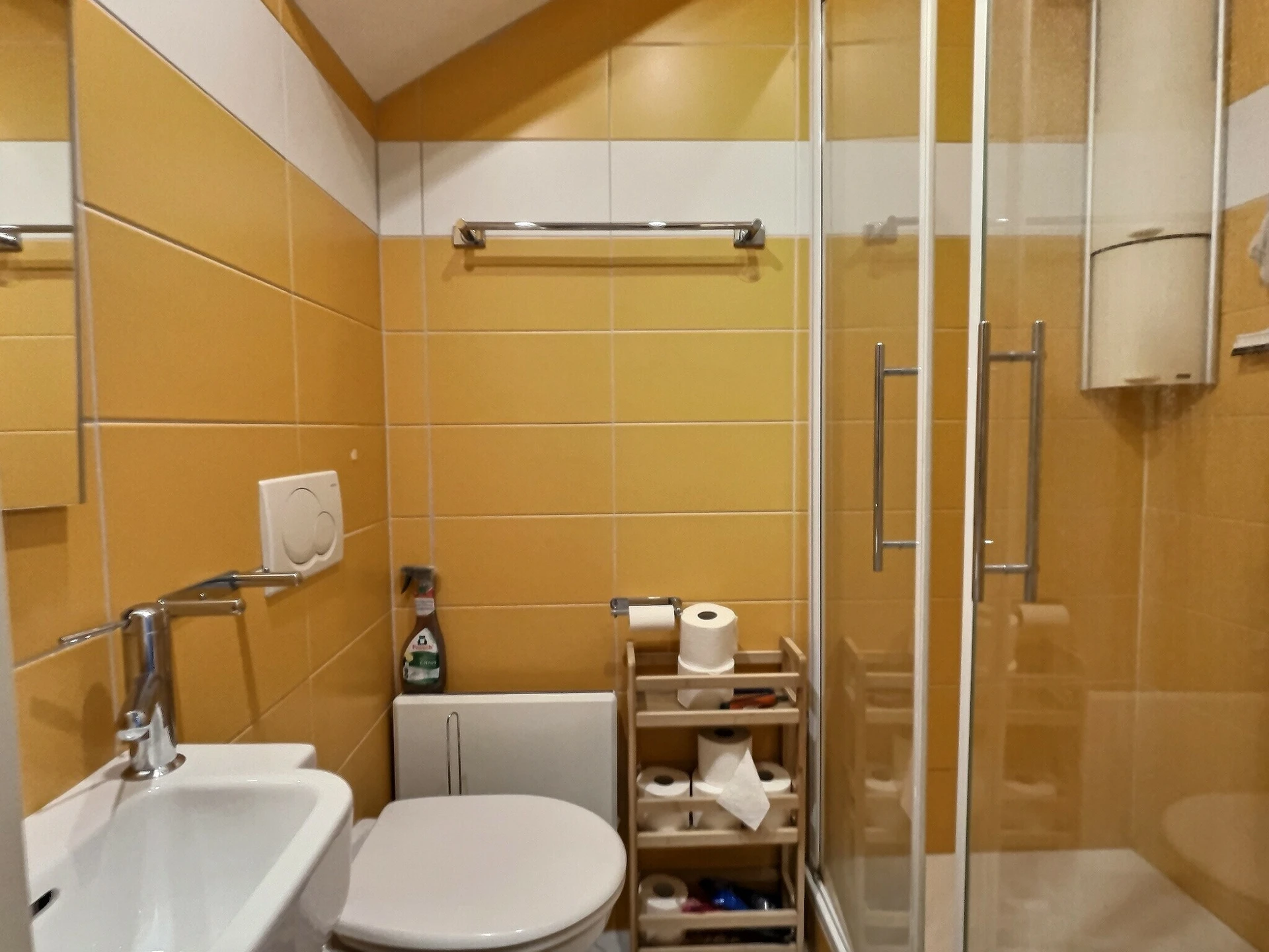 Kleines gelb-weiß gefliestes Badezimmer mit Dusche und WC