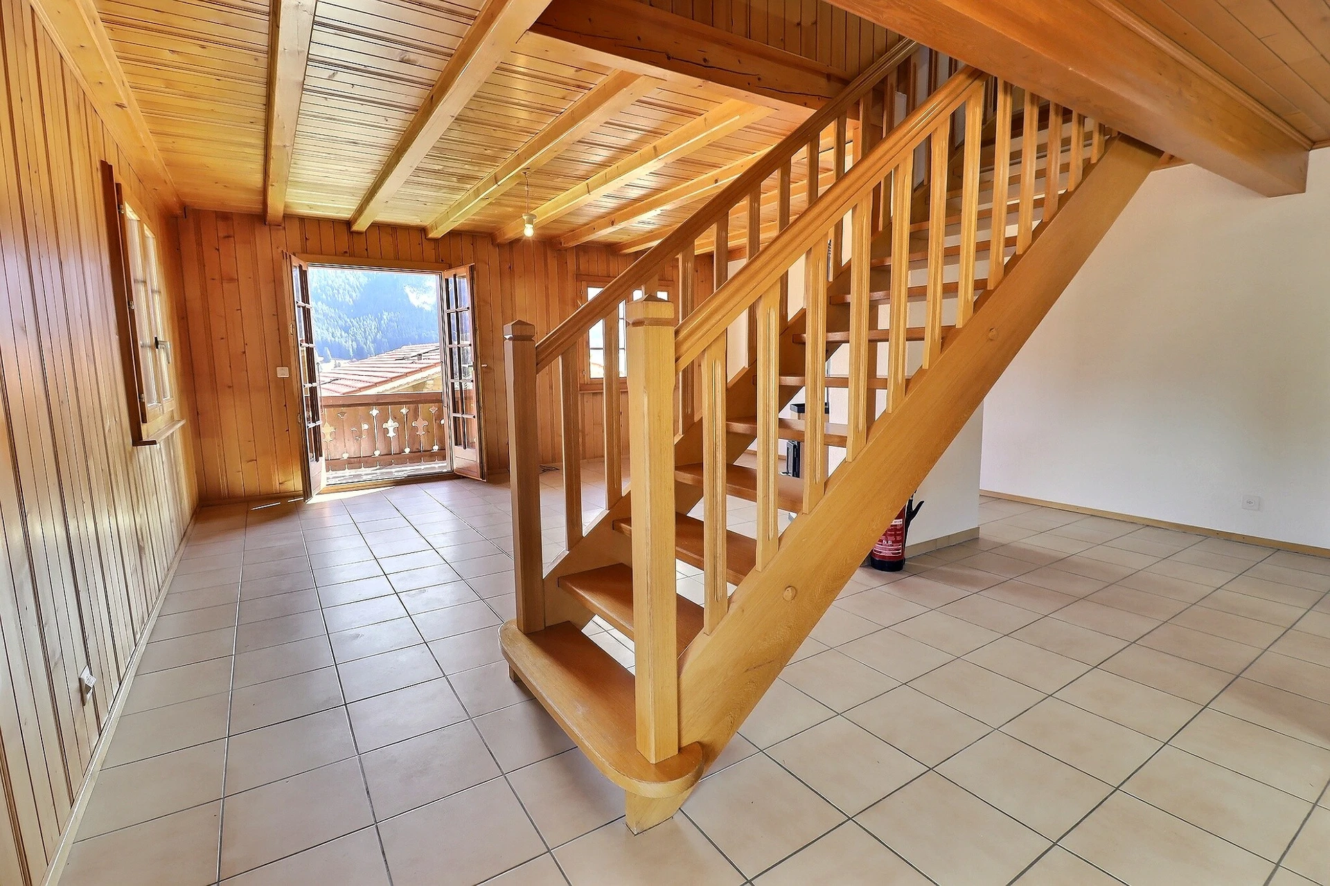 Heller Eingangsbereich mit Holztreppe und Balkonblick