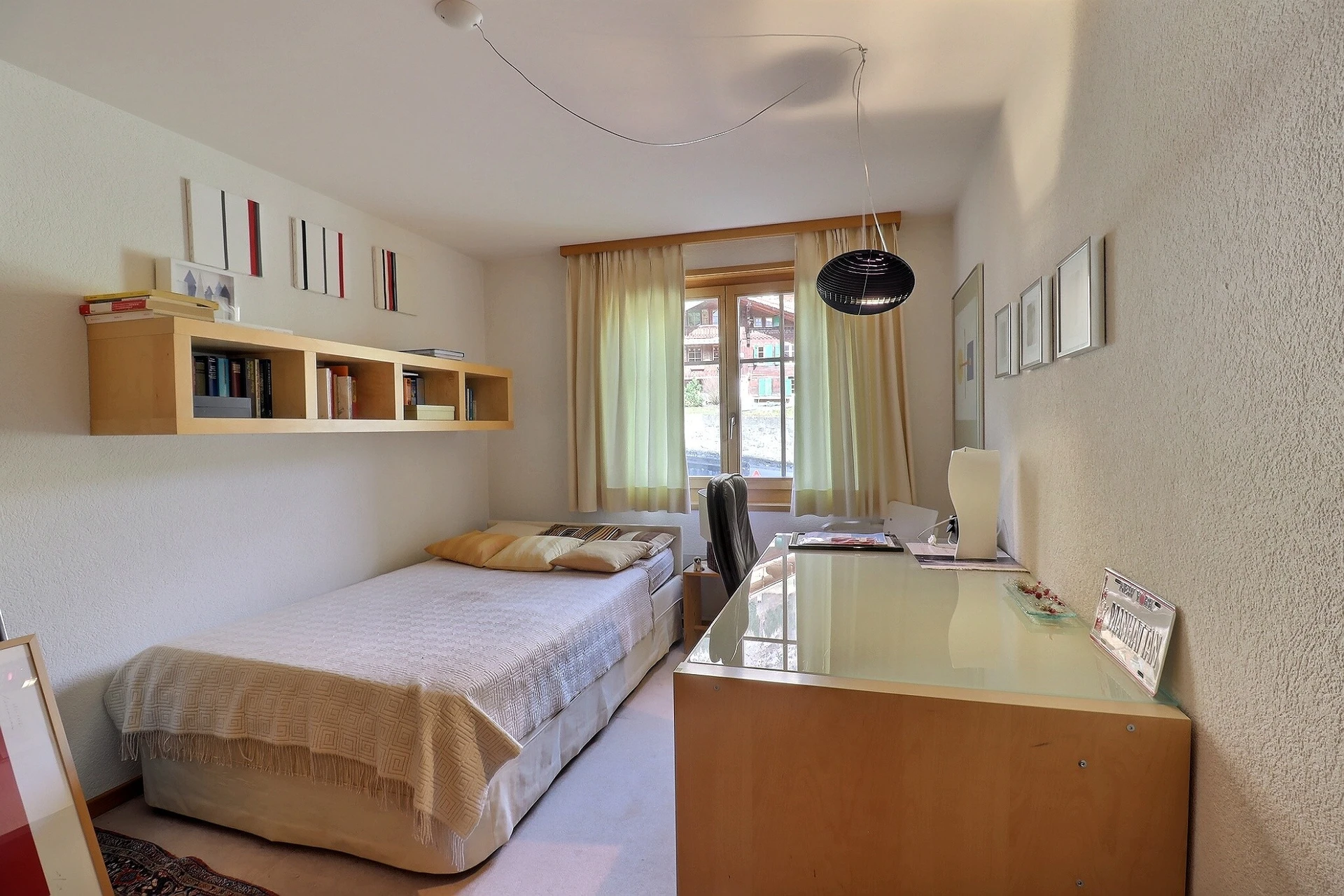Kleines, möbliertes Schlafzimmer mit Schreibtisch und Fenster