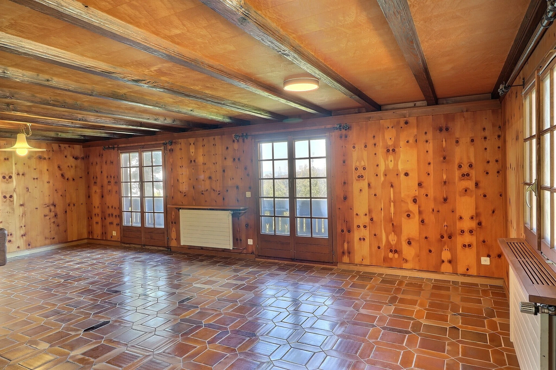Rustikaler Raum mit Holzverkleidung und Terrakottaboden