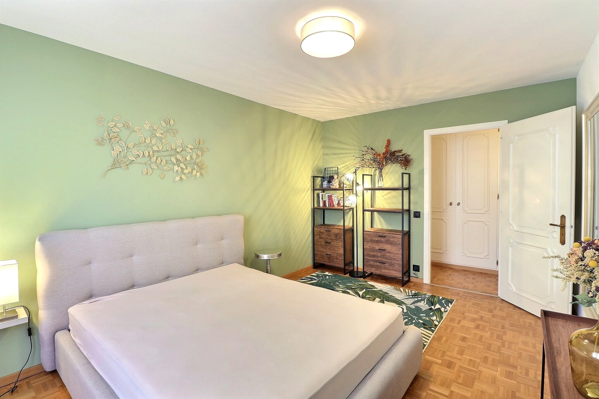 Helles Schlafzimmer mit grün gestrichenen Wänden und Holzparkett