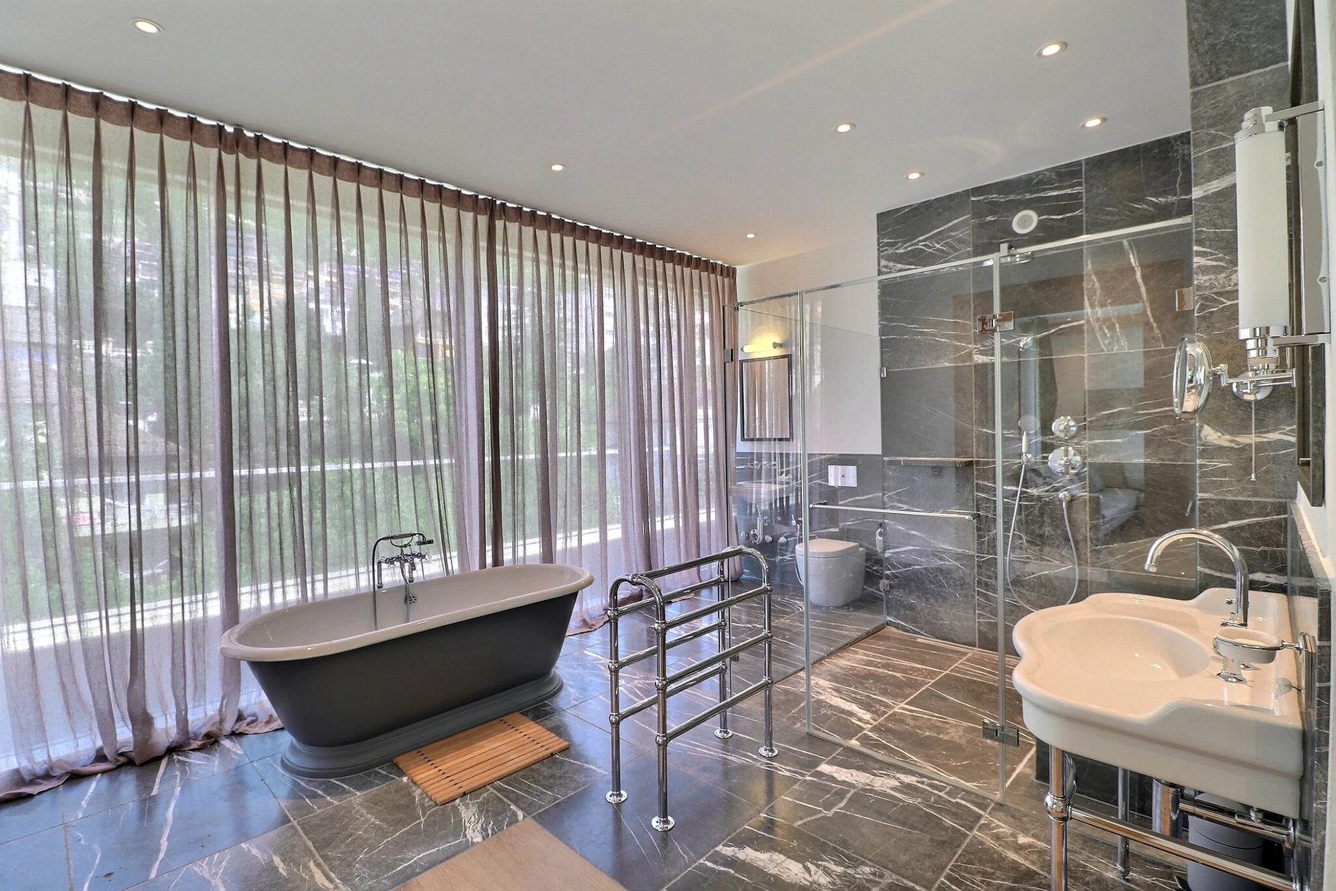 Luxuriöses Badezimmer mit freistehender Wanne und Großformatfliesen