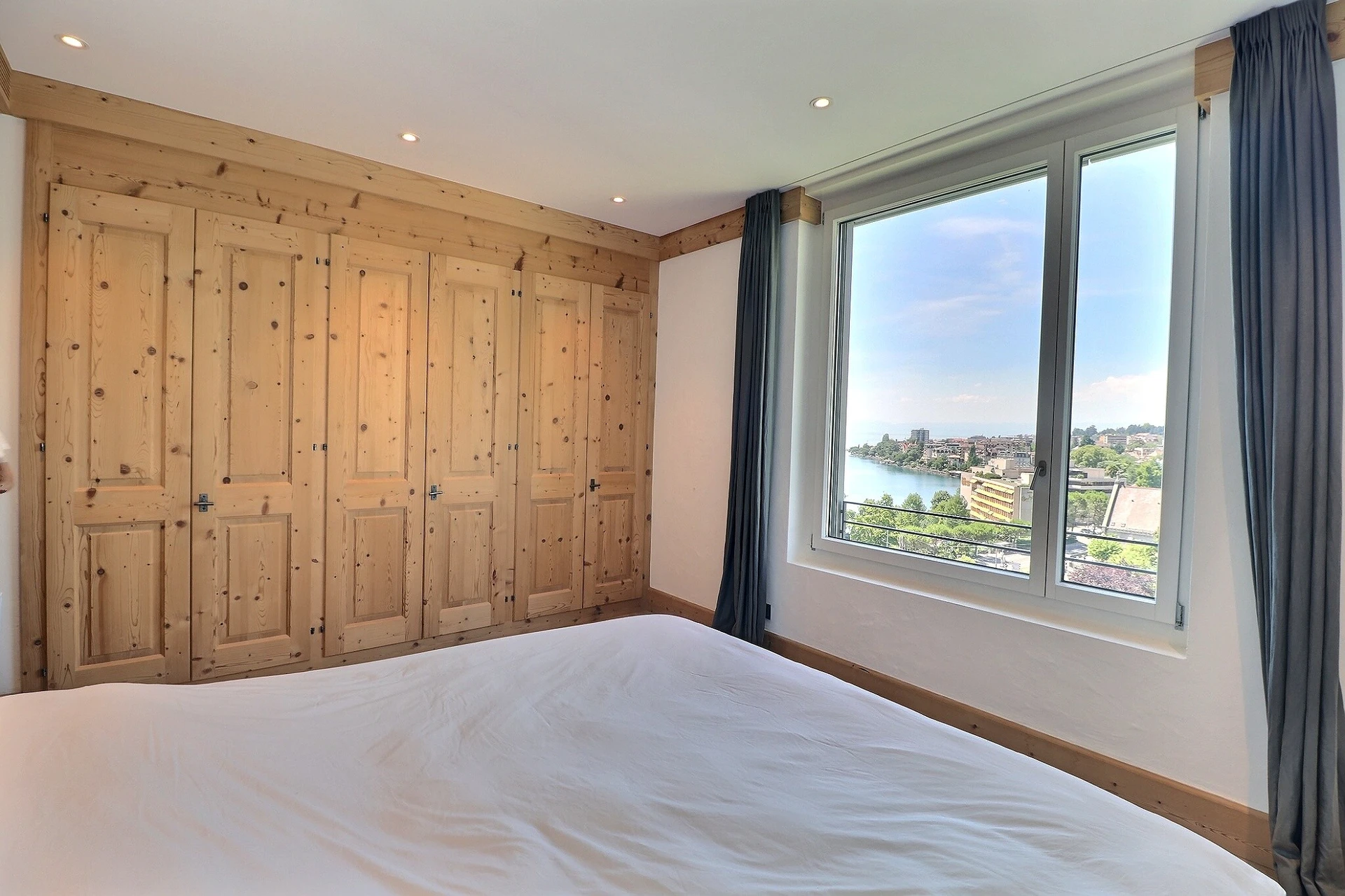 Helles Schlafzimmer mit Holzverkleidung und Ausblick auf Wasser