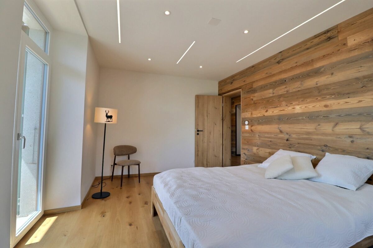 Helles Schlafzimmer mit Holzwand und großen Fenstern