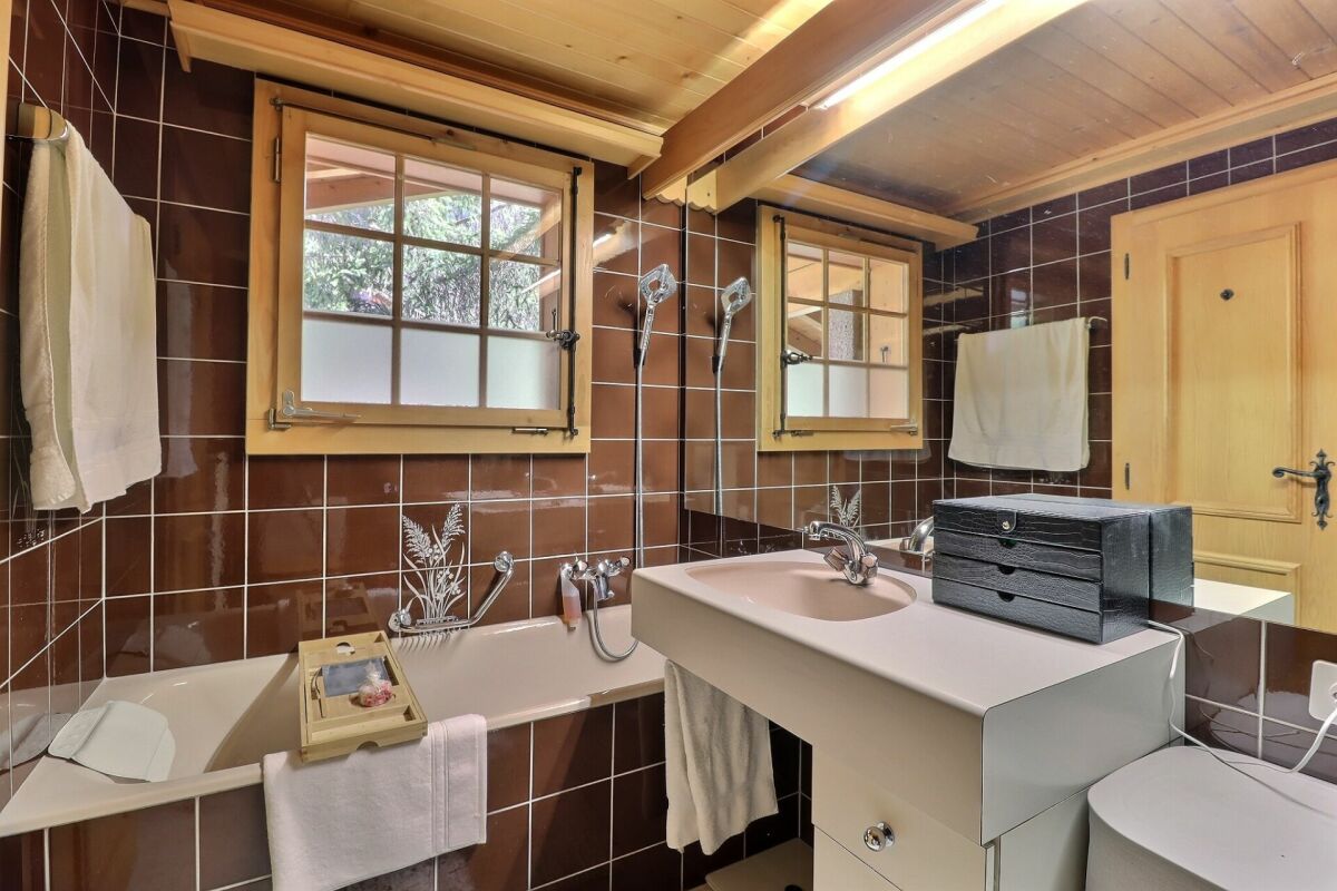 Badezimmer mit Badewanne und Holzfenstern
