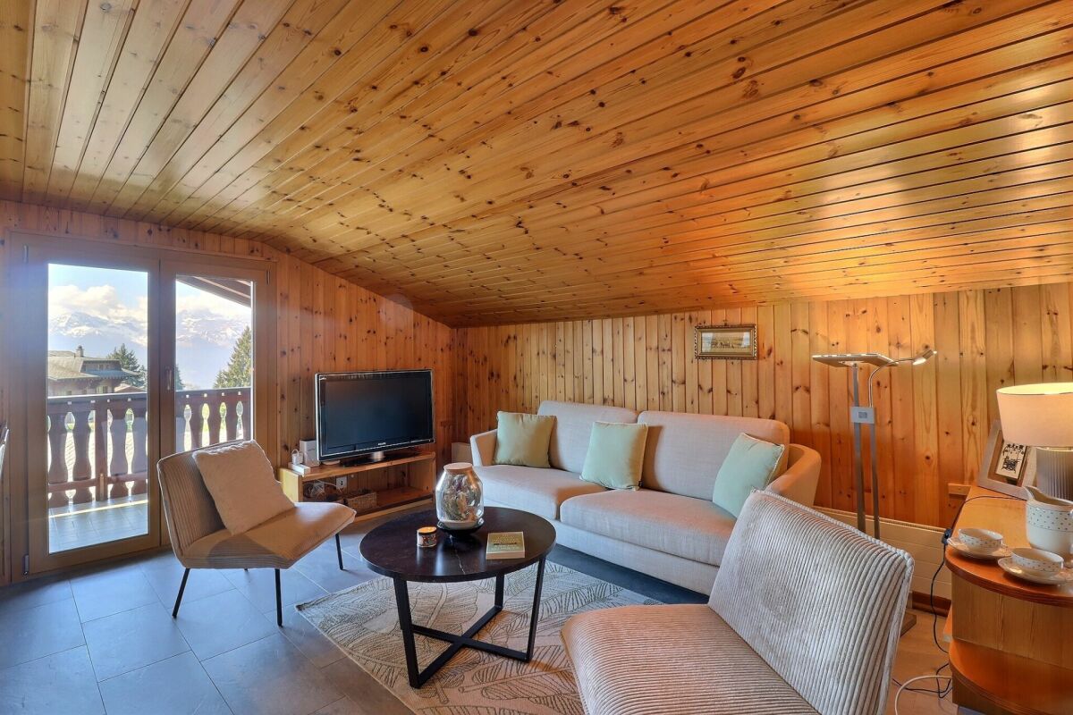 Gemütliches Wohnzimmer mit Holzvertäfelung und Bergblick