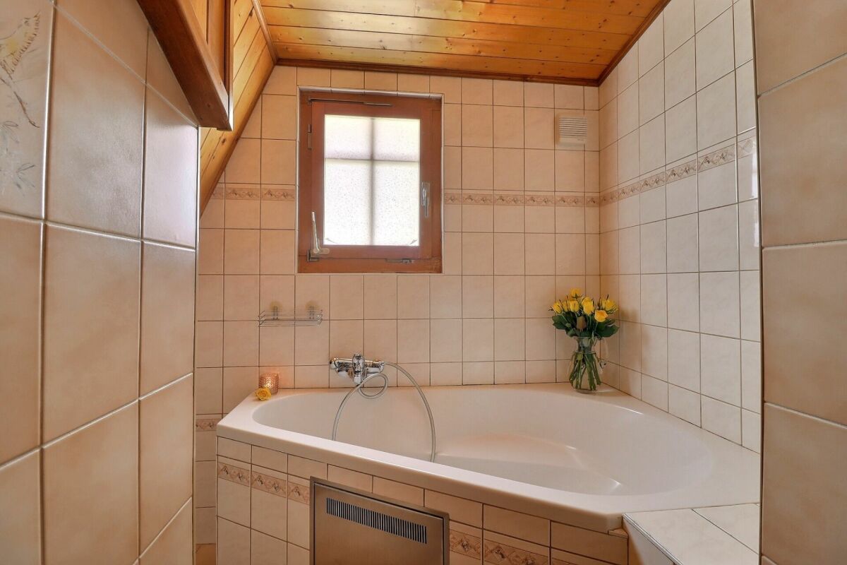 Badezimmer mit Badewanne und Holzdecke
