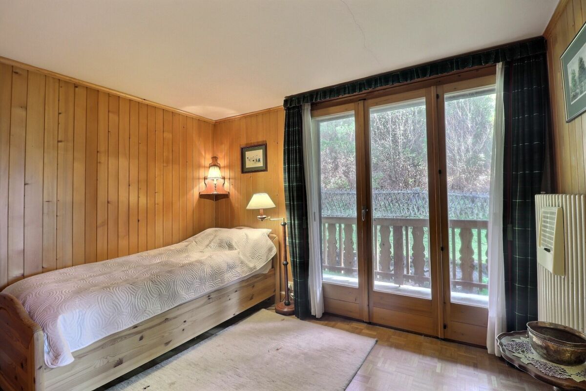 Gemütliches Schlafzimmer mit Holzvertäfelung und Balkonblick