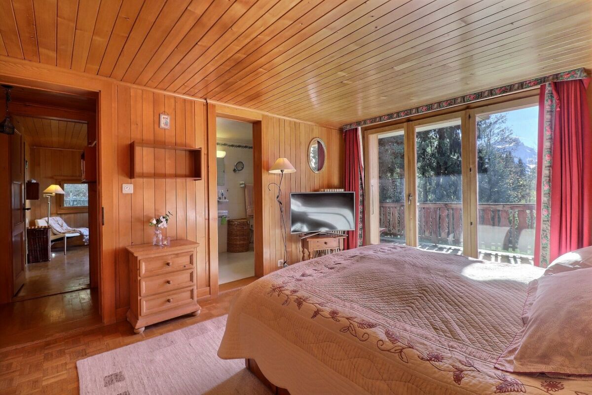 Gemütliches Schlafzimmer mit Holzvertäfelung und Balkonblick