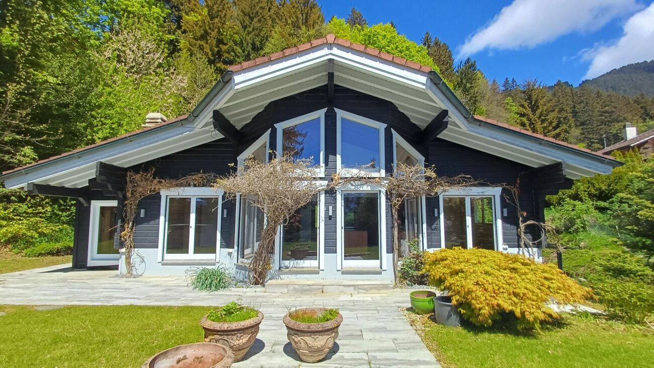 Dunkles Holzhaus mit Satteldach und großer Verglasung