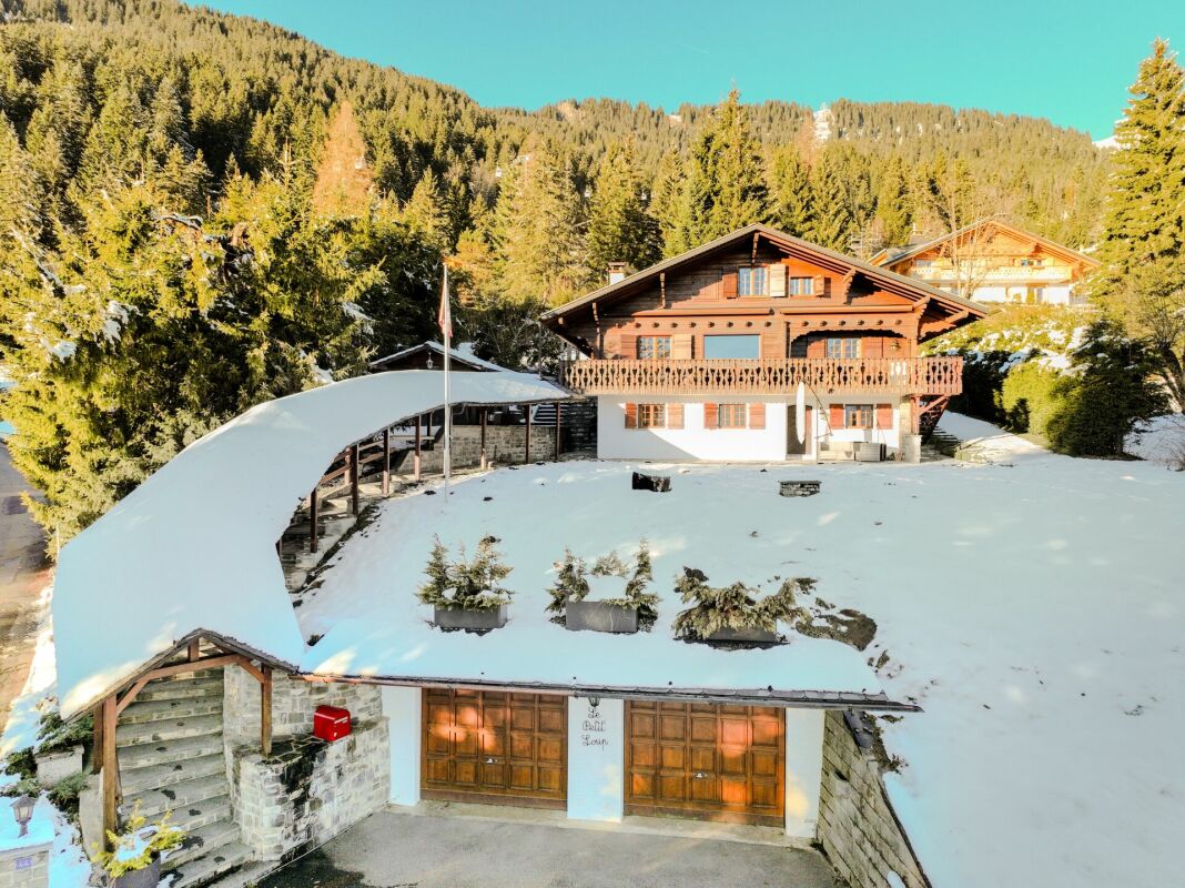 Alpenchalet mit verschneitem Hanggrundstück