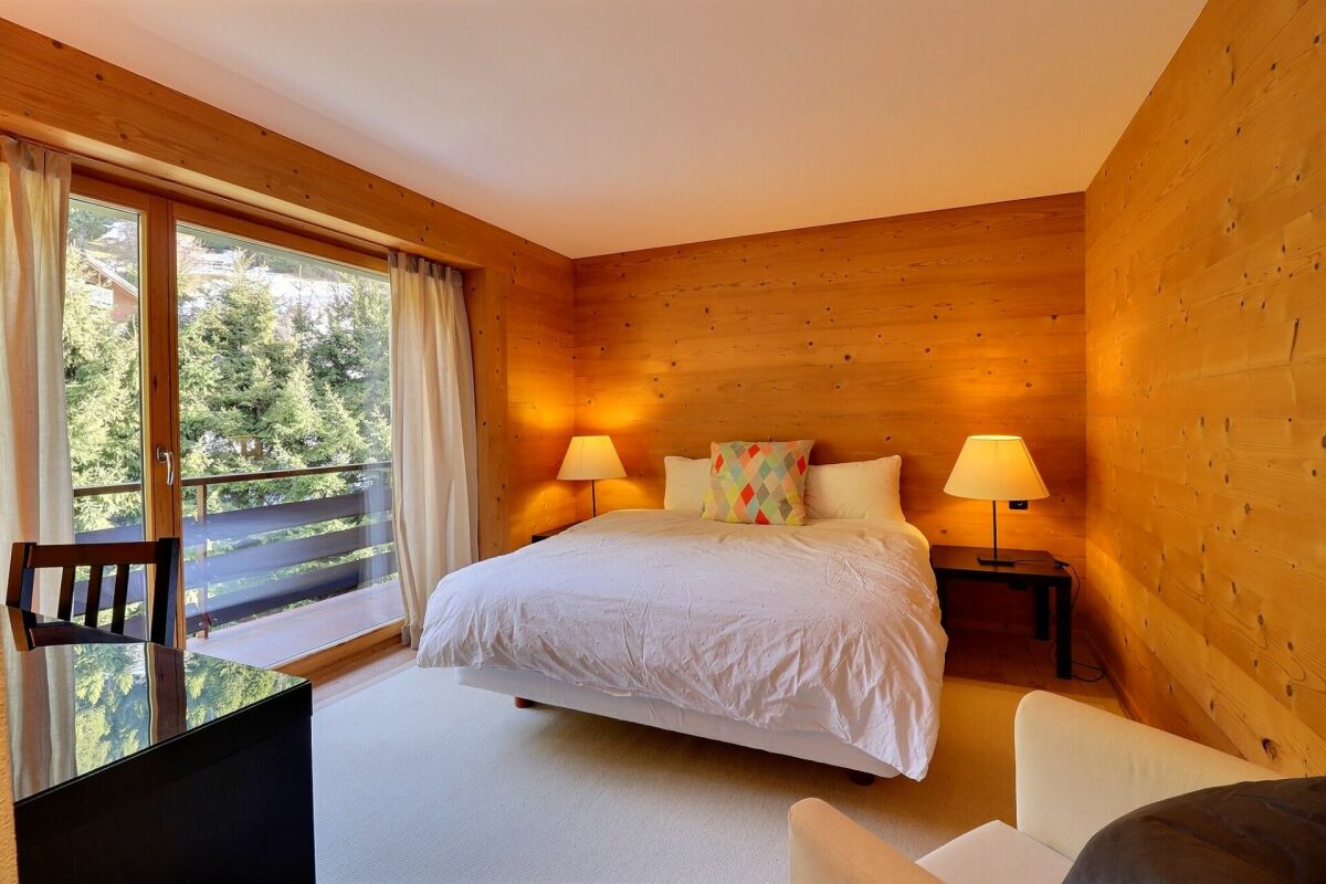 Gemütliches Schlafzimmer mit Holzvertäfelung und Balkonblick