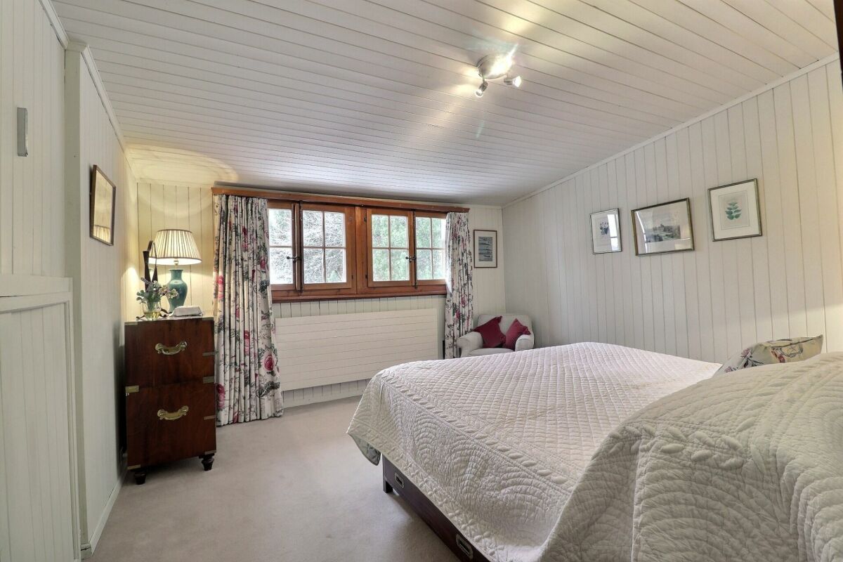 Gemütliches Schlafzimmer mit Holzfenster und weißer Vertäfelung