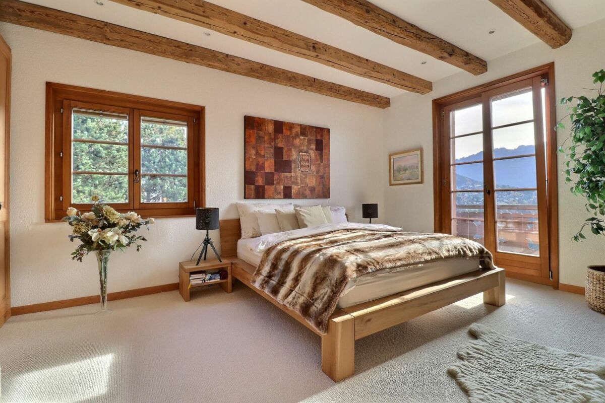 Helles Schlafzimmer mit Holzbalkendecke und Bergblick
