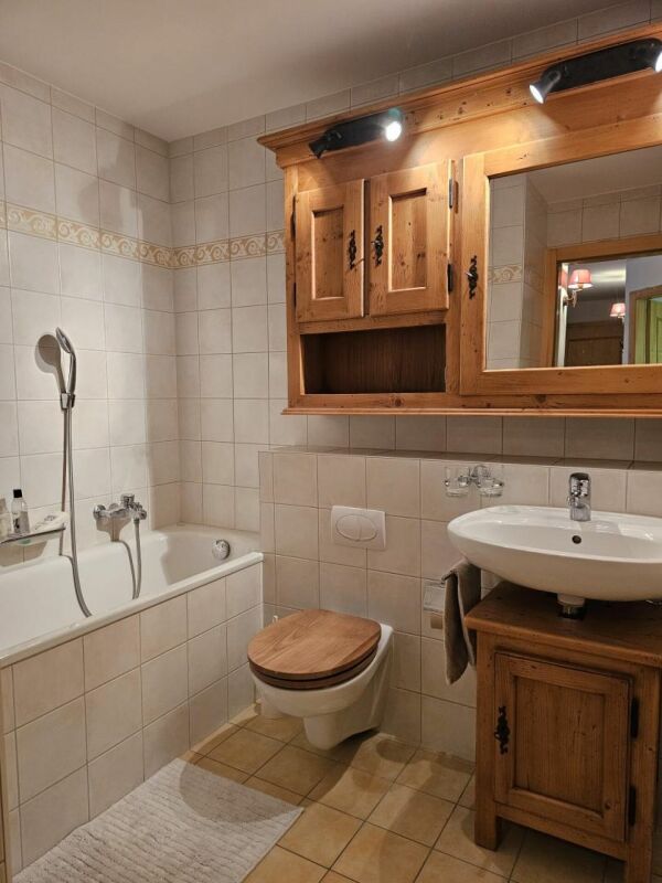Rustikales Badezimmer mit Holzschrank und Badewanne