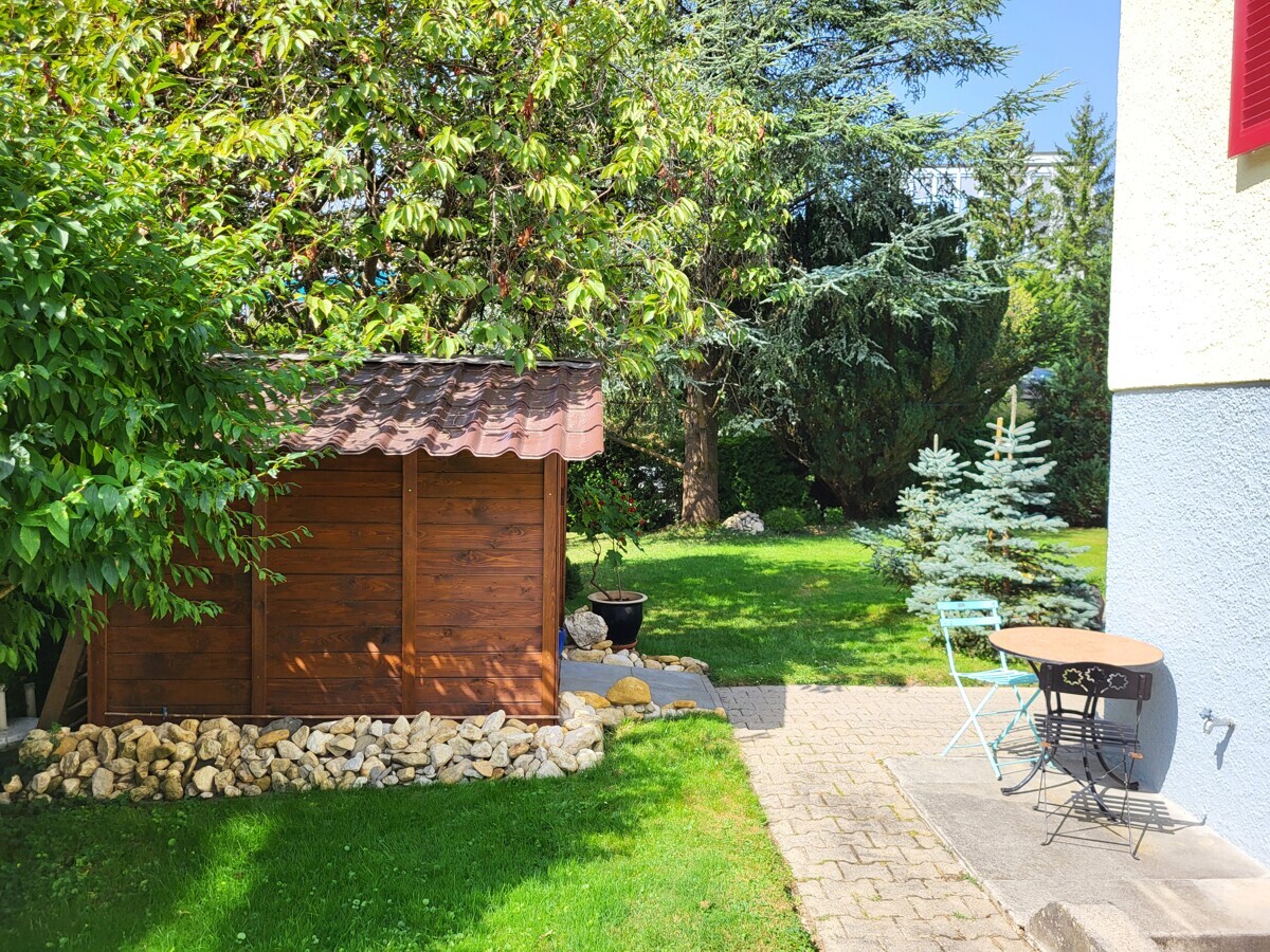 Garten mit Sitzplatz neben Holzschuppen